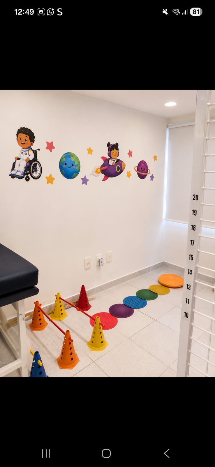 Sala de fisioterapia com cones, tapetes e adesivos do universo
